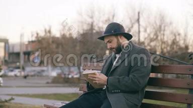 有创意的年轻作家戴着帽子，穿着外套，坐在城市街道上，用<strong>钢笔</strong>为他未来的<strong>书写</strong>笔记